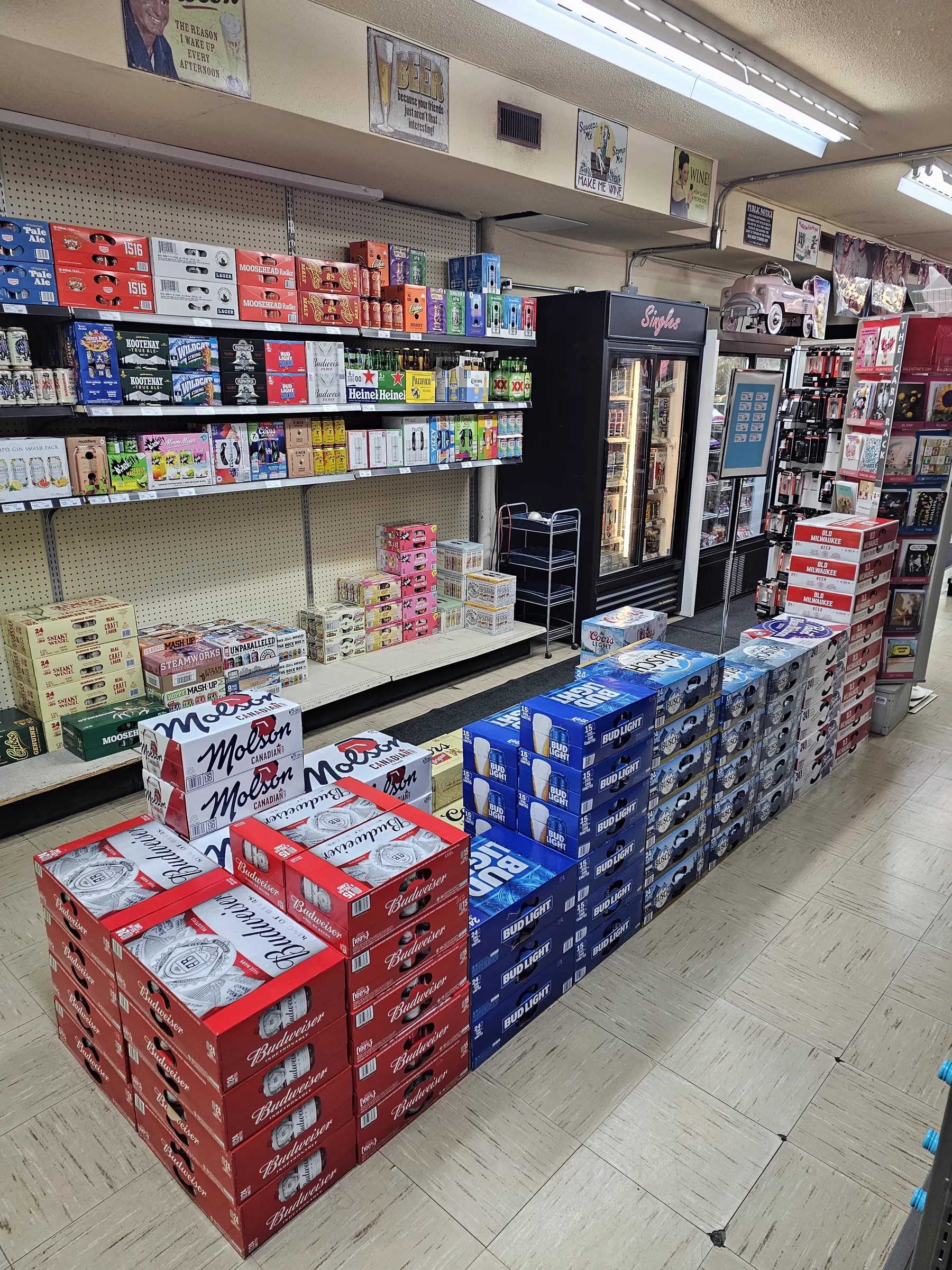 Stacked cases of beer beside a cooler in the store liquor section